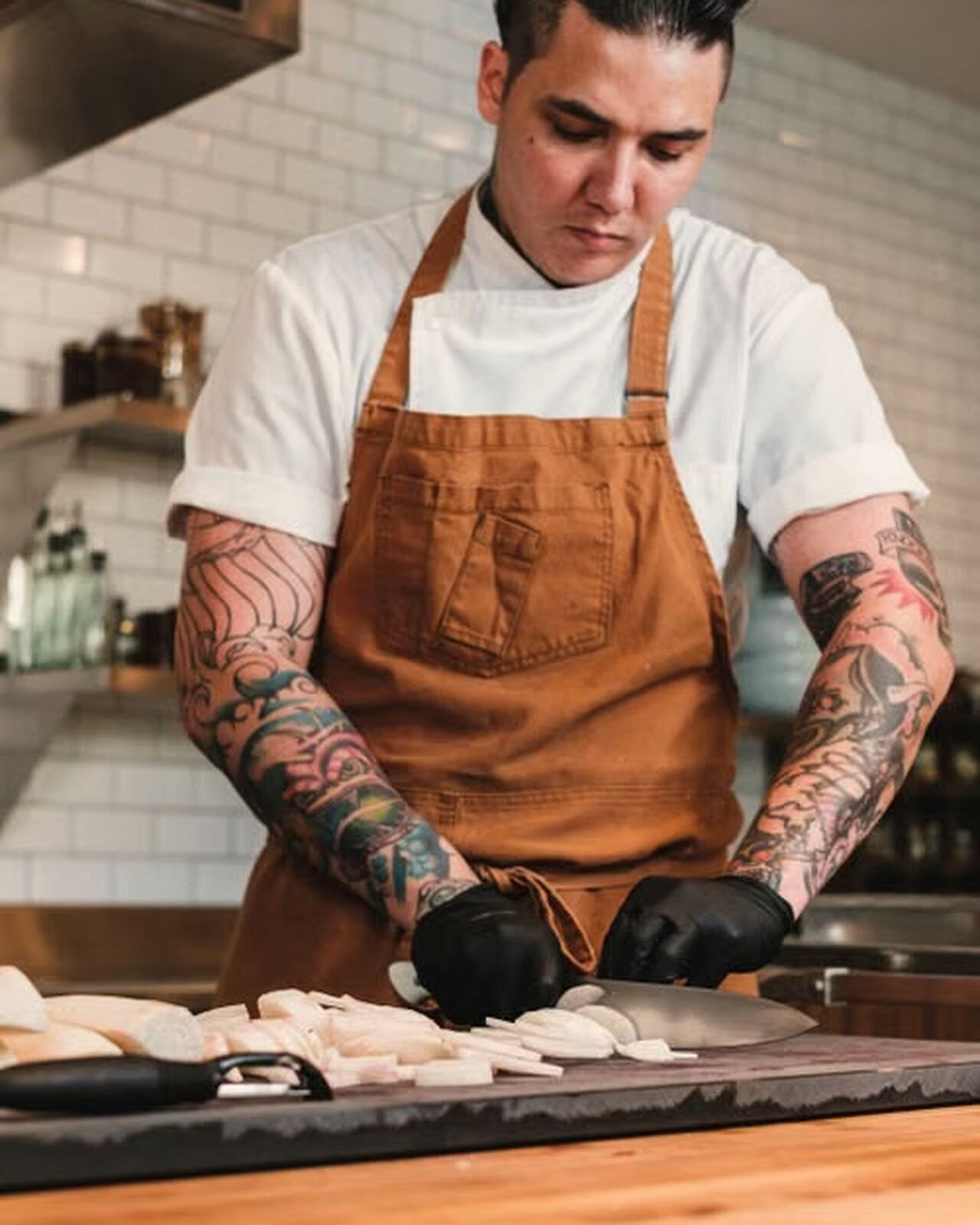 Placeholder portrait — a chef in working whites in a kitchen, to be replaced with real team photography at go-live