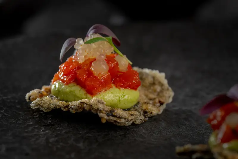Tomato tartare with clear pearls and a green purée on a crisp wafer, finished with micro herbs by myCHEF Cape Town