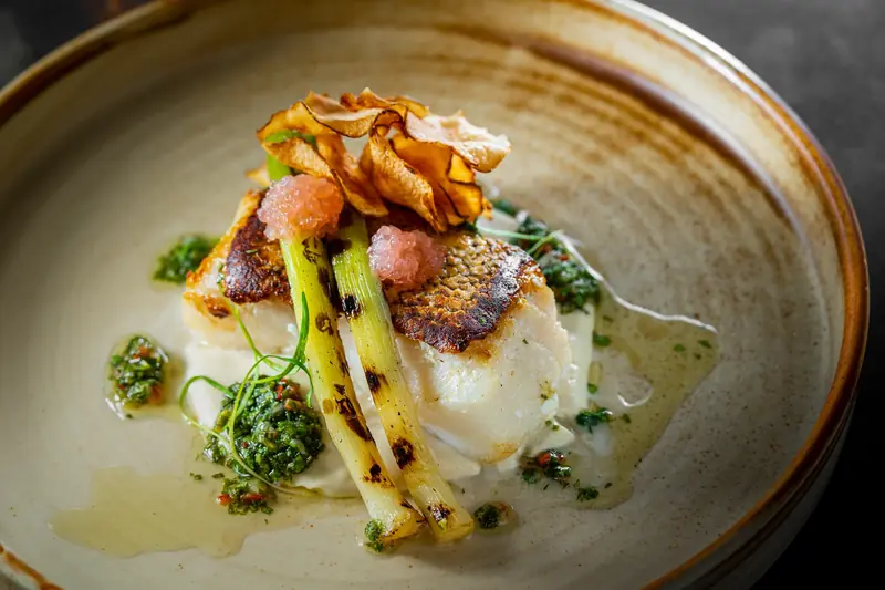 Seared white fish on leeks with a herb salsa and a crisp garnish by myCHEF Cape Town