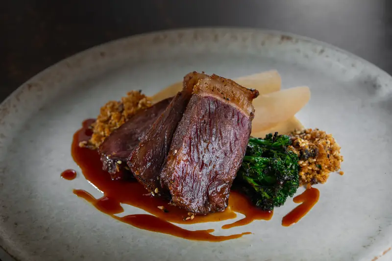 Braised meat with a glossy jus, dark greens and a crumb by myCHEF Cape Town