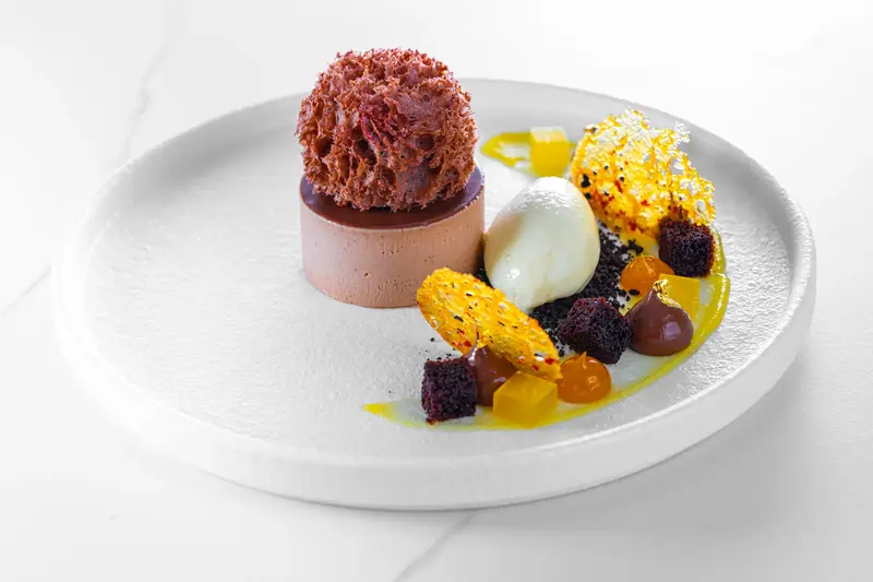 Plated dessert with a crumble-topped mousse, ice cream quenelle and sponge pieces by myCHEF Cape Town